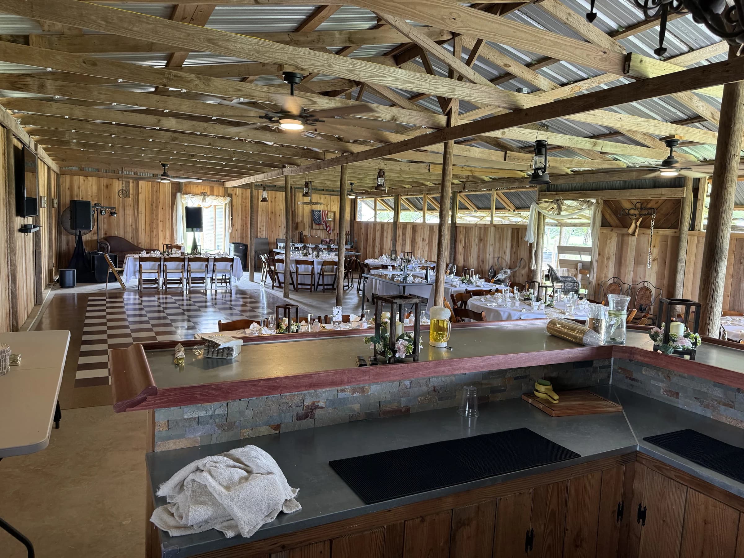 A view from behind the barn bar across the checkered dance floor and reception tables