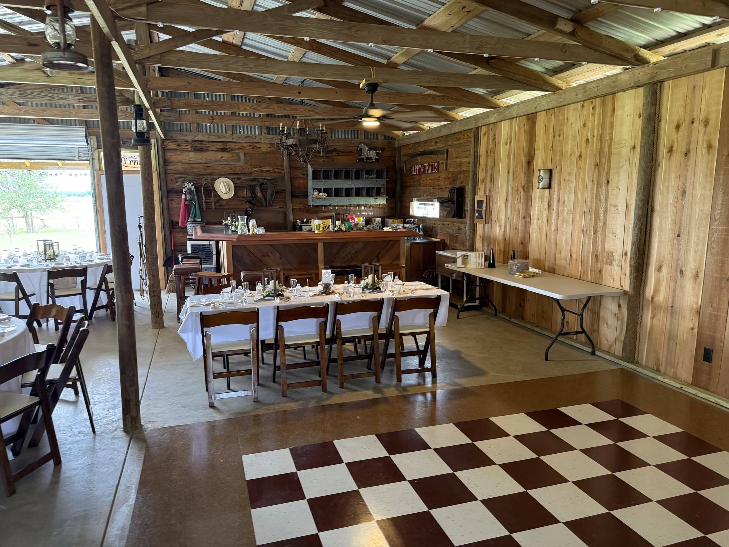 The custom wooden bar and dining tables beside the barn’s checkered dance floor