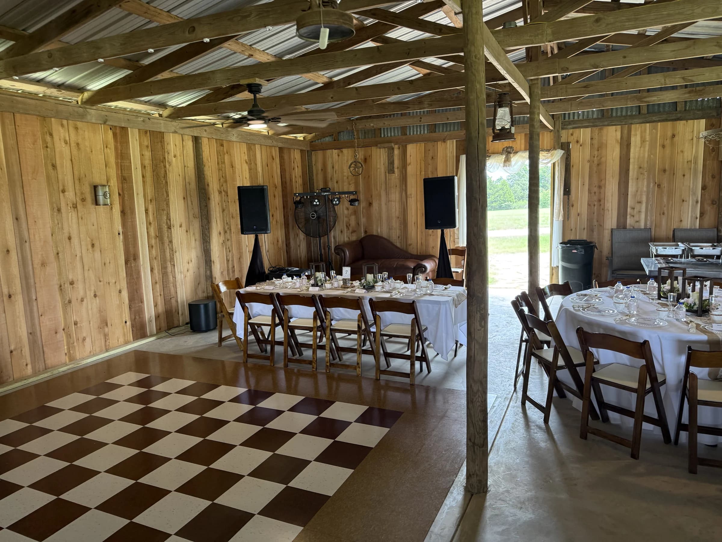 The barn’s checkered dance floor beside reception tables and wooden walls