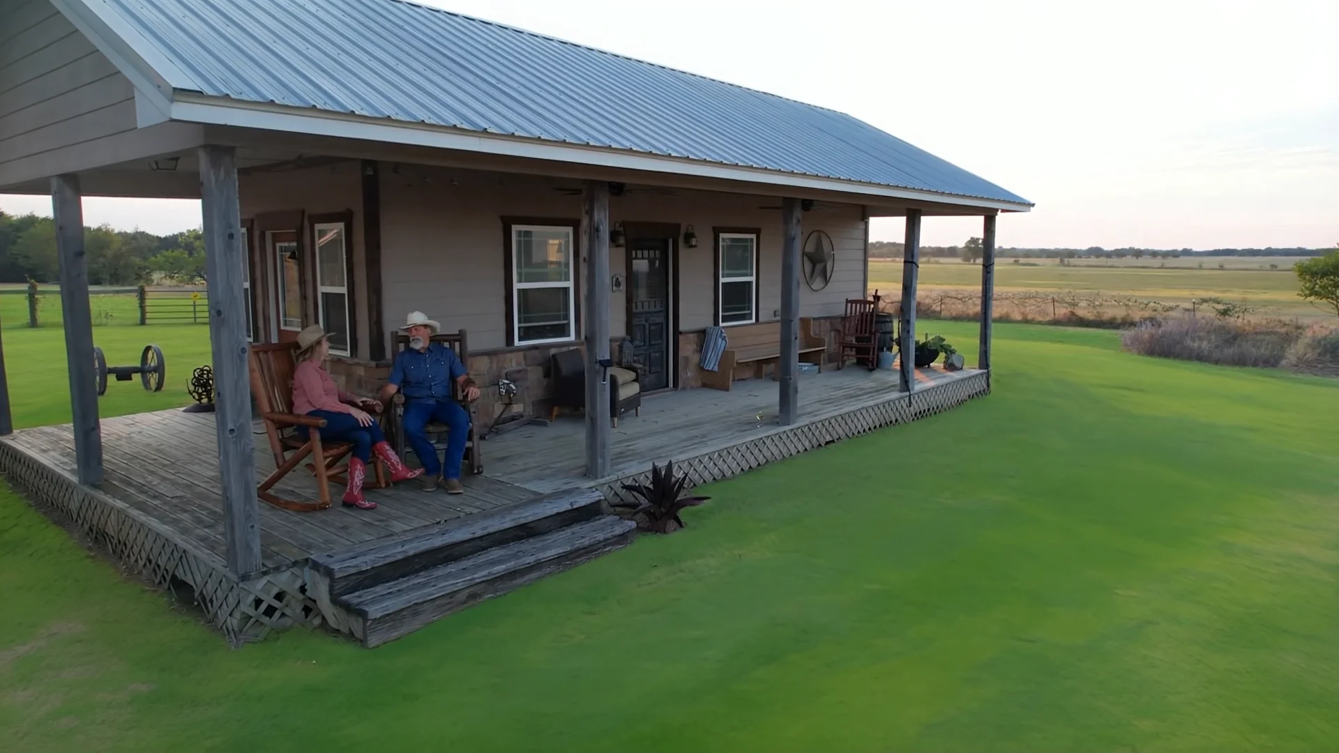 The Western-inspired bunkhouse and its covered porch, with two people seated outside