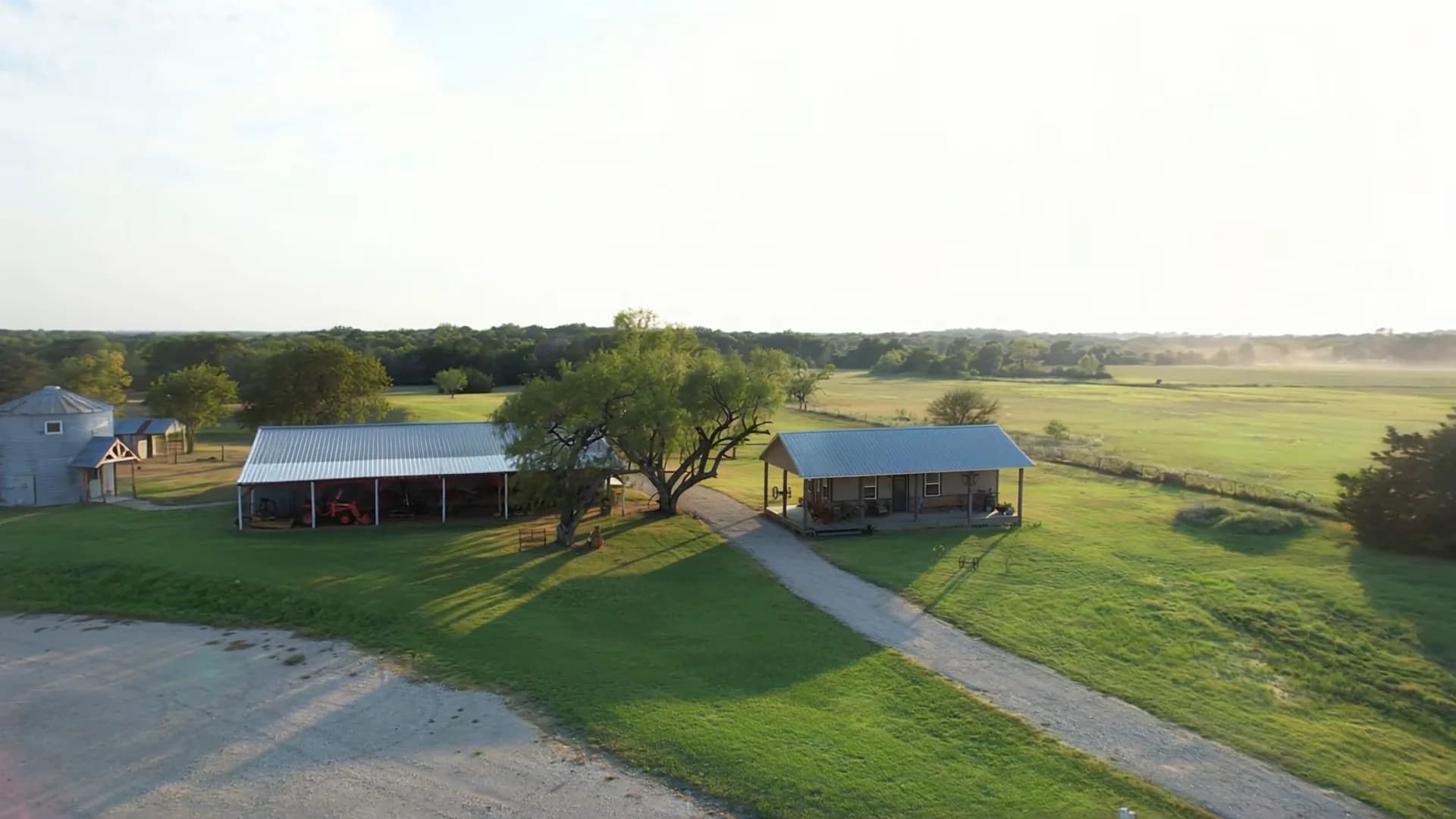 The barn, grain-bin suite, and bunkhouse around a green lawn and gravel drive