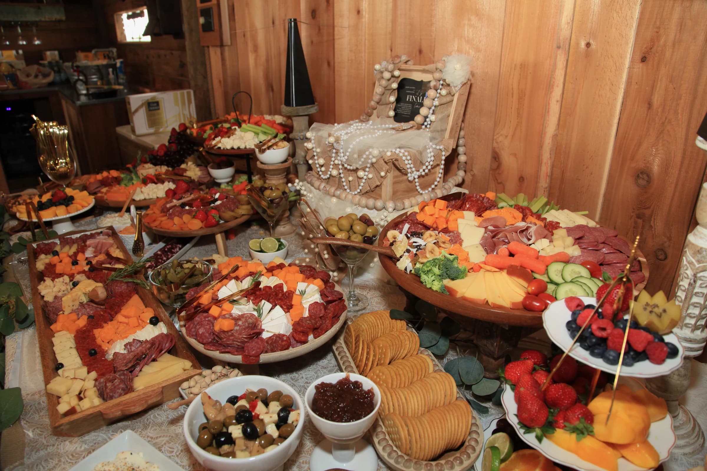 A colorful reception spread of fruit, cheese, and snacks arranged inside the barn