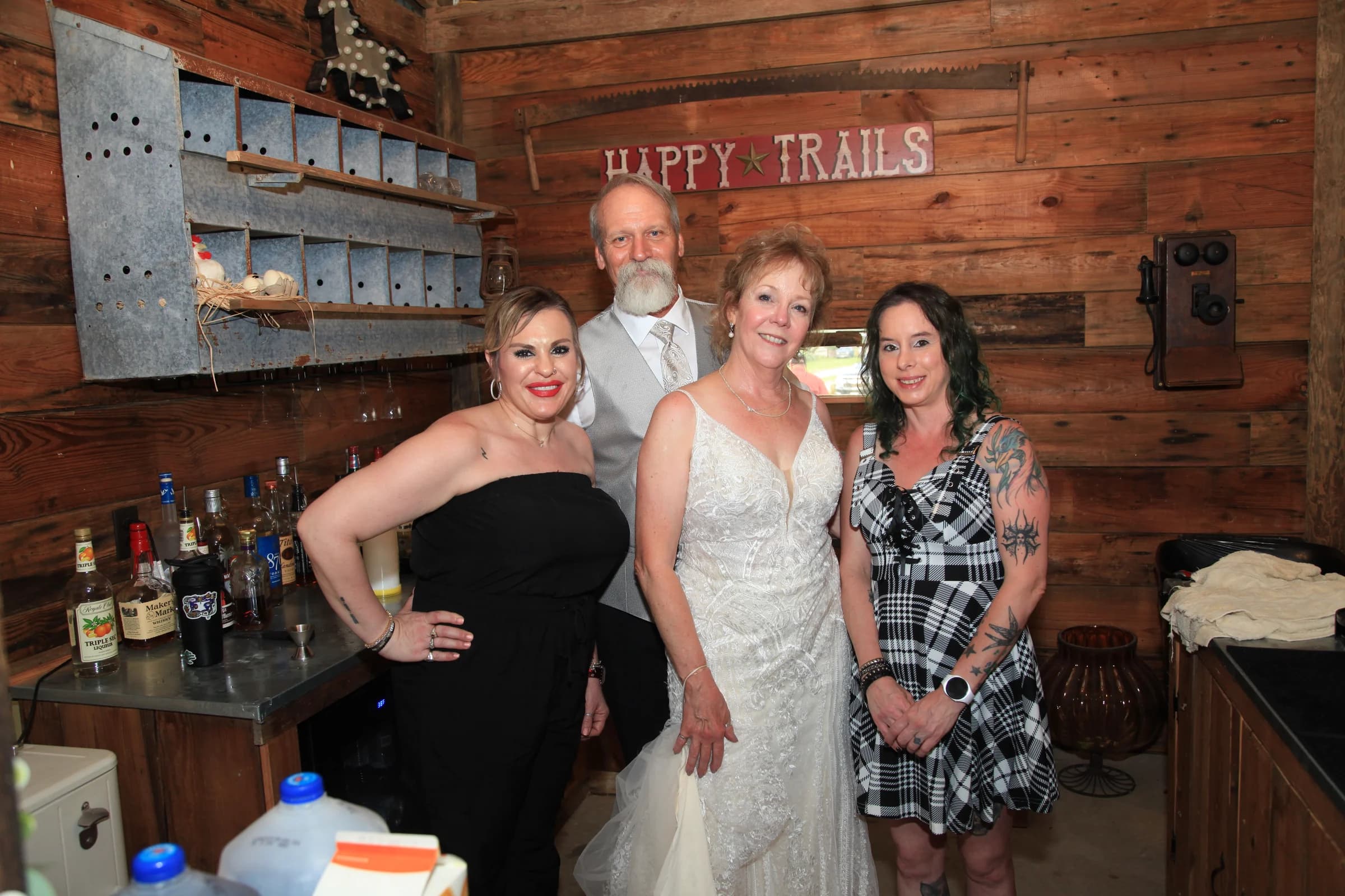 Four people, including a bride and groom, posing together at the Happy Trails bar